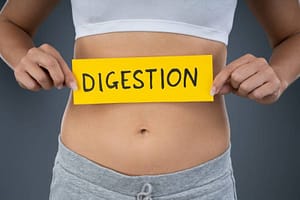 Woman with stomach pain holding a piece of paper saying “digestion.”