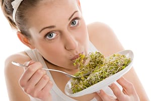 A veggie junkie helping herself with a side plate of sprouts
