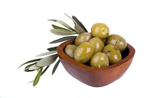 Green olives in a wooden bowl with an olive branch