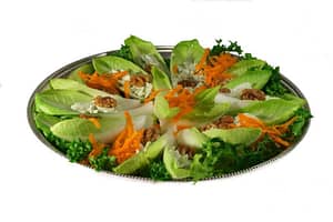 A salad with walnuts, carrot, endive and lettuce on a silver tray.