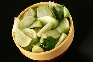 Freshly cut tomatillo slices in a bowl with cilantro