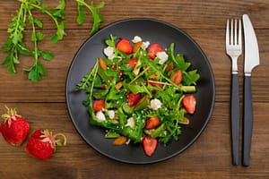Salad with arugula, strawberries, cottage cheese, and olive oil