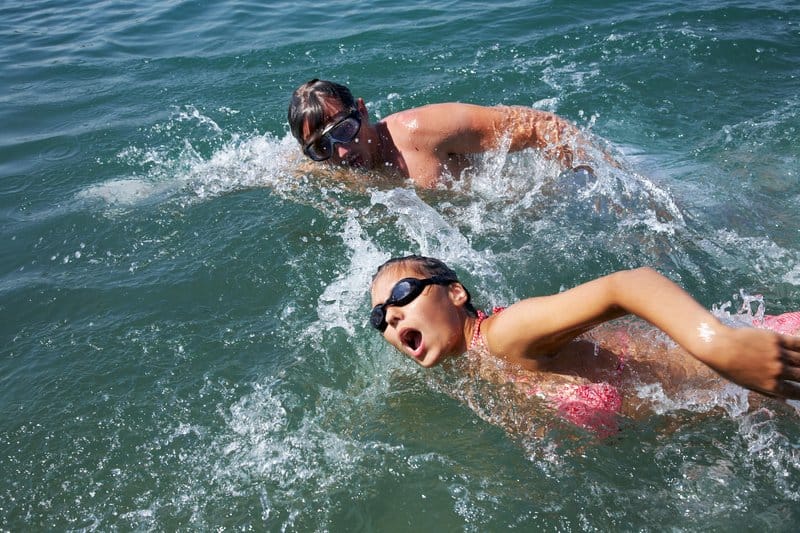 man and woman are swimming together in open water