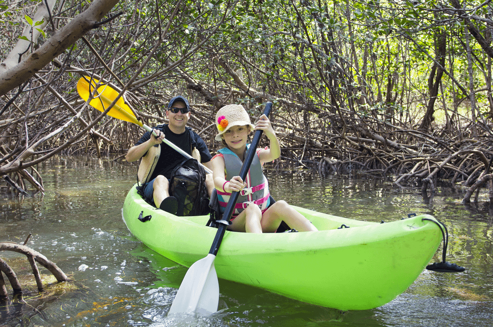 Two people paddling a single kayak on a lake